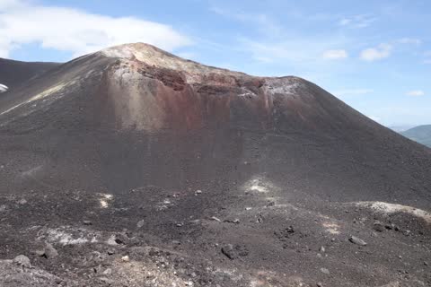 The red, yellow and grey crater wall of Cerro Negro above a black slope of ash