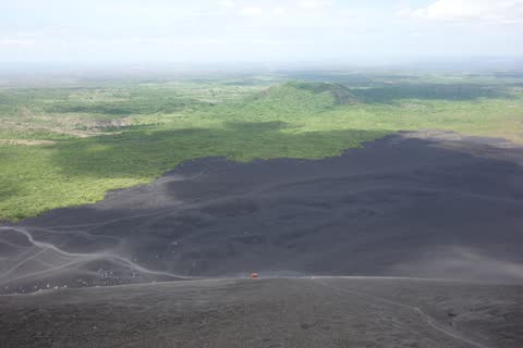 Looking down the black slope of the descent to the green plain, the ash scored with earlier tracks