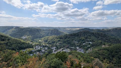 View from the Goethepunkt down to Obernhof and the wooded Lahn Valley under fair-weather clouds