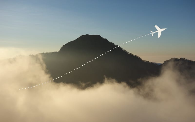 A plane above a sea of clouds with its dashed flight path behind it