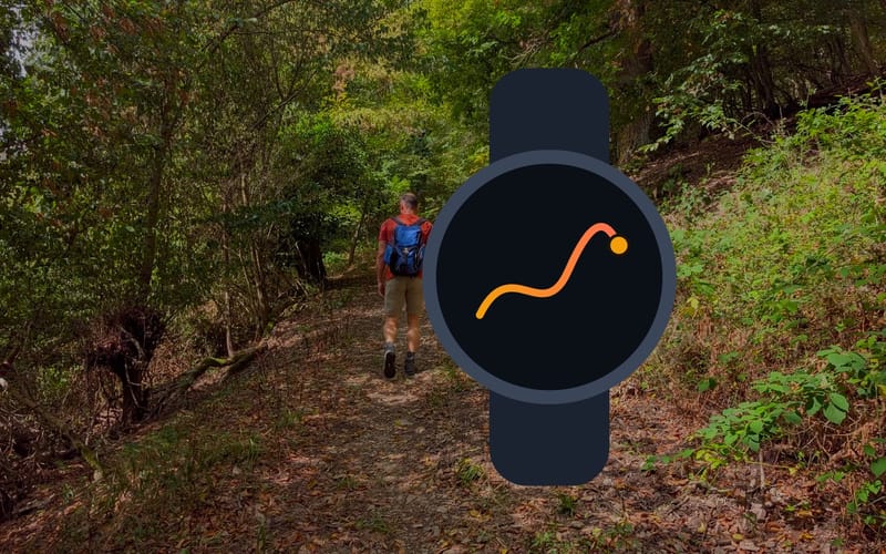 A sports watch with a route on its face in front of a forest path